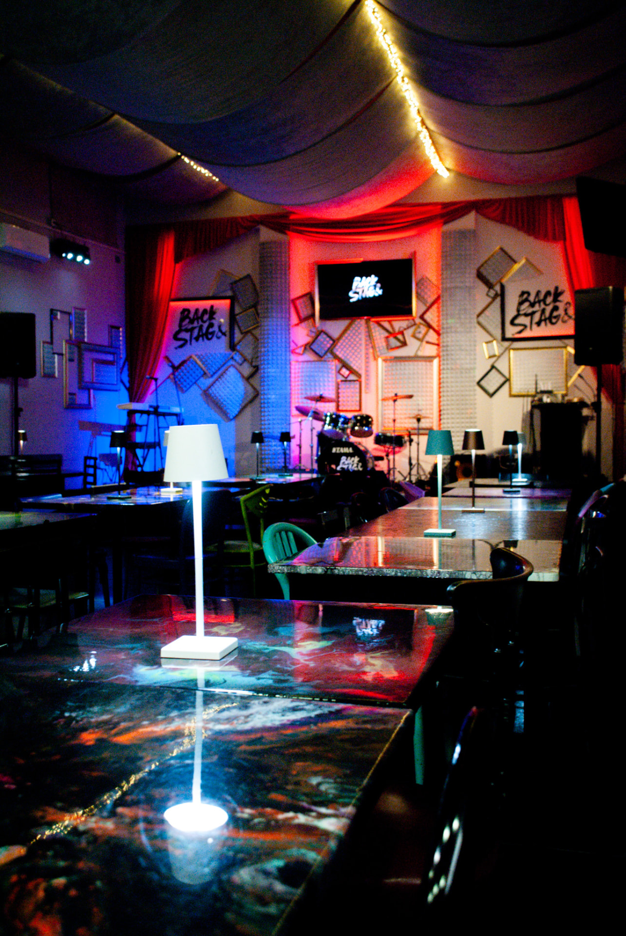 Sala del Backstage Binasco con palco e tavoli colorati
